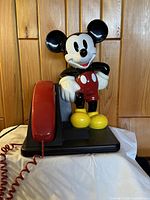 Front view of the vintage 1990 Disney Mickey Mouse shaped desk telephone showing the full figure with red handset attached to base.