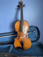 Front view of violin in case with bow visible, showing body and fittings