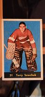 Front image of the 1960-61 Parkhurst hockey card featuring Terry Sawchuk in goalie gear for Detroit Red Wings against blue background, with card number 31 and player name.