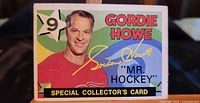 Front side of the 1971-72 OPC Gordie Howe special collector's card featuring a photo and printed autograph on a colorful background.