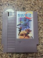 Front of the grey Nintendo NES cartridge showing the Super C game label with Konami branding and colorful artwork.