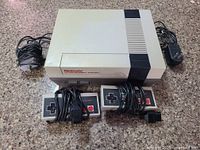 Top view of Nintendo Entertainment System console with 2 controllers and cables laid out on surface