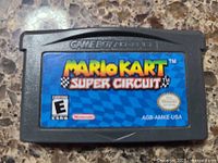 Close-up of original Mario Kart Super Circuit game cartridge for Game Boy Advance showing label and plastic cartridge body.
