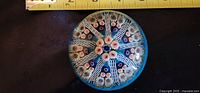Top view of the glass paperweight showing the intricate millefiori flower pattern inside, approximately 3 inches in diameter.