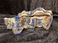 Side view showing rough textured surface with blue and tan glazing, coral shaped form.