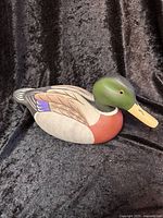 Side view of the hand-painted wooden duck decoy showing the detailed paint and green head with yellow beak