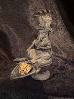 Full view of metal Ganesha statue seated on a decorated base with compartment containing necklace and charm