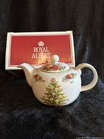 Porcelain Royal Albert teapot in original box, showing full view of teapot with Christmas tree and floral pattern.