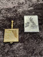 Metal travel ashtray engraved with Florida and silver tone matchbook cover with map of Great Britain and Ireland.