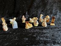 Twelve Wade Whimsies nursery rhyme themed porcelain figurines on black fabric
