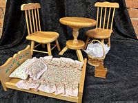 Photo showing entire wooden doll furniture set including bed with bedding, table, two chairs, basket with cloth, and magazine rack.