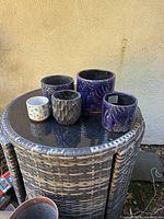 Overview of the five ceramic planters showing three blue embossed leaf pattern planters, one black textured planter, and one small white cactus pattern planter.
