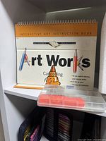 Art Works interactive art instruction book focused on cartooning with colorful pencils and markers visible.