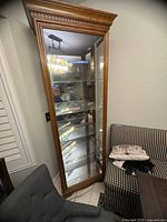 Full view of the china cabinet showing wood frame, glass door, and glass shelves inside.