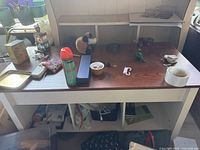 Cocktail table with various items on the top surface and lower shelf, showing the table's size and condition.