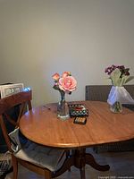 Wooden oval dining table with one leaf inserted between two sections of the table top. The table is polished and in good condition. Chair and small items on table not included.