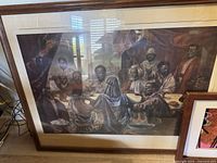 Framed print showing multiple figures in a muted color scene, largest print about 2x3 feet