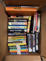 Top-down photo of a box containing a collection of middle grade books, including Horrible Histories, Murderous Maths, Eyewitness Books Ancient Greece, Harry Potter, and various graphic novels and series.