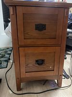 Front view of one wooden mission style night stand showing two drawers with dark metal handles.