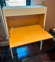 Front view of the modern kids secretary desk, white frame with natural wood fold-down writing surface open, showing the interior workspace and supports.