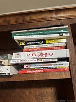 Stack of assorted books on shelf with titles on garden design, menopause, marketing, publishing, and digital photography.