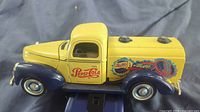 Side view of the Pepsi-Cola diecast truck showing yellow and blue paint with vintage Pepsi-Cola graphics.