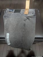 Folded black denim jeans showing back pocket and tags