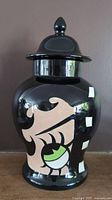 Full view of the large black ceramic ginger jar with painted Betty Boop face and lid.