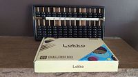 Lokko Brain Training Challenge Box and vintage wood abacus displayed on a wooden surface against a dark wall.