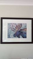 Framed moose watercolour painting hung on wall with visible matt and dark frame