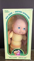 Full view of the vintage 1985 Glo Kids doll in original box showing yellow packaging with green text and doll inside.