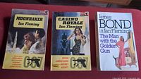 Set of three vintage James Bond paperback books: Moonraker, Casino Royale, and The Man with the Golden Gun.