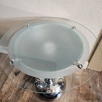 Top view showing the round clear glass top, frosted glass underlayer, and chrome mounting pegs.