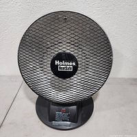 Front view of Holmes HeatSafe space heater showing mesh protective grill with logo in center.