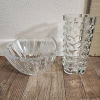 Large clear lead crystal bowl and tall geometric lead crystal vase side by side on wooden floor