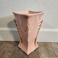 Front and side view showing Art Deco wing/fan relief patterns and glossy pink ceramic finish.
