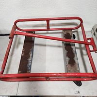 Side-angle view of red metal frame with square rectangular base and partial rust.