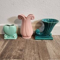 Front view of three mid century pottery vases showing varying shapes and pastel colors