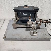 Front view of Montgomery Ward bench grinder showing grinding wheel, tool rest, sharpening guide, and metal base with some rust and wear.