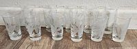 Front view of all 11 glasses arranged in a row showing etched floral and leaf patterns