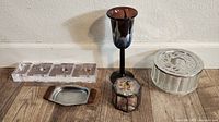 Five vintage candle holders and one glass metal cigarette holder arranged on wooden surface.