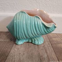 Side view of vintage Roseville Pottery seashell planter showing turquoise exterior and pink interior.