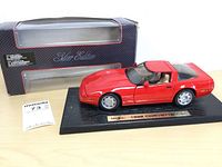 Red die-cast model of 1996 Corvette on black display base with Maisto plaque and original box in background.
