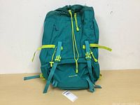 Front view of a teal and lime green youth 40 litre backpack with visible main compartment zipper, buckles, and straps.