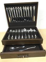 Full view of wooden chest open showing knives, forks, spoons and bottom drawer with serving pieces