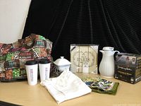 Photo showing the full lot including coffee carafe, Jumping Bean coffee, candy or nut dish, apron, cake plate, colorful tote bag, two travel coffee tumblers, and framed Paris sign.