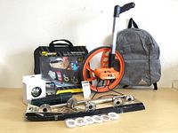 Photo of full lot showing all items: Road Trip trunk organizer, Keson measuring wheel, grey backpack, four towel racks, white flashlight, and small speaker.