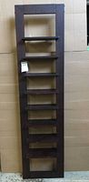 Full view of tall, narrow brown wooden display shelf with seven shelves in rectangular frame.