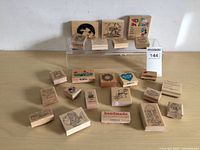 Lot of 19 wooden block rubber stamps arranged on and around a clear plastic stand, varying themes visible including animals, hearts, messages, and characters.