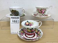 Front view of three tea cups and their matching saucers displayed on a clear stand.